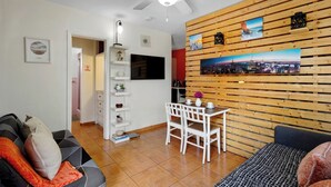 Una sala de estar moderna con comedor, ventilador de techo y un cuadro de un paisaje urbano en la pared.