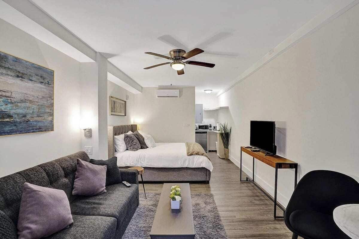 Una habitación moderna y luminosa con una cama, un sofá, una mesa de centro y una televisión.