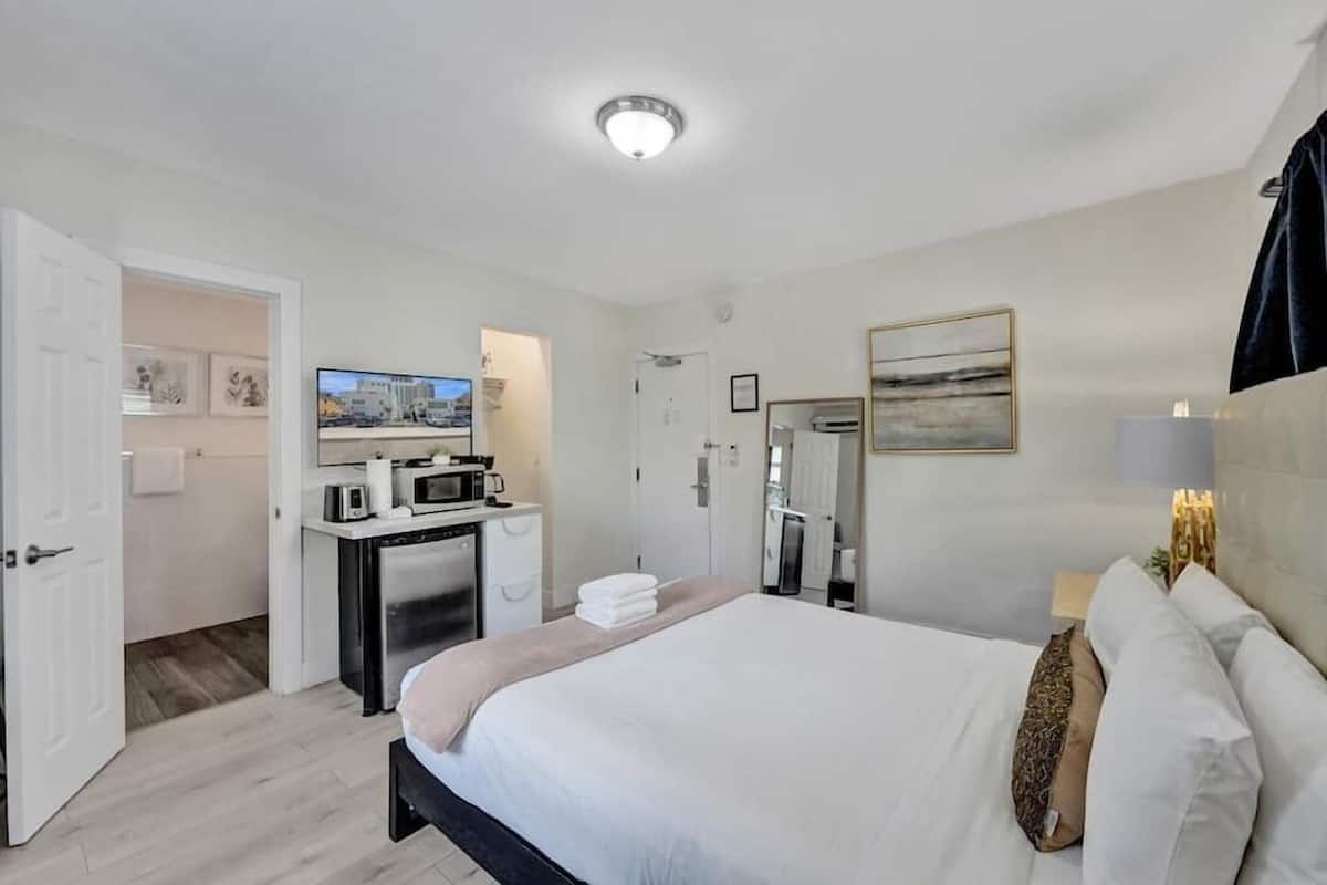Una habitación de hotel con cama, escritorio con computadora, microondas y televisión.
