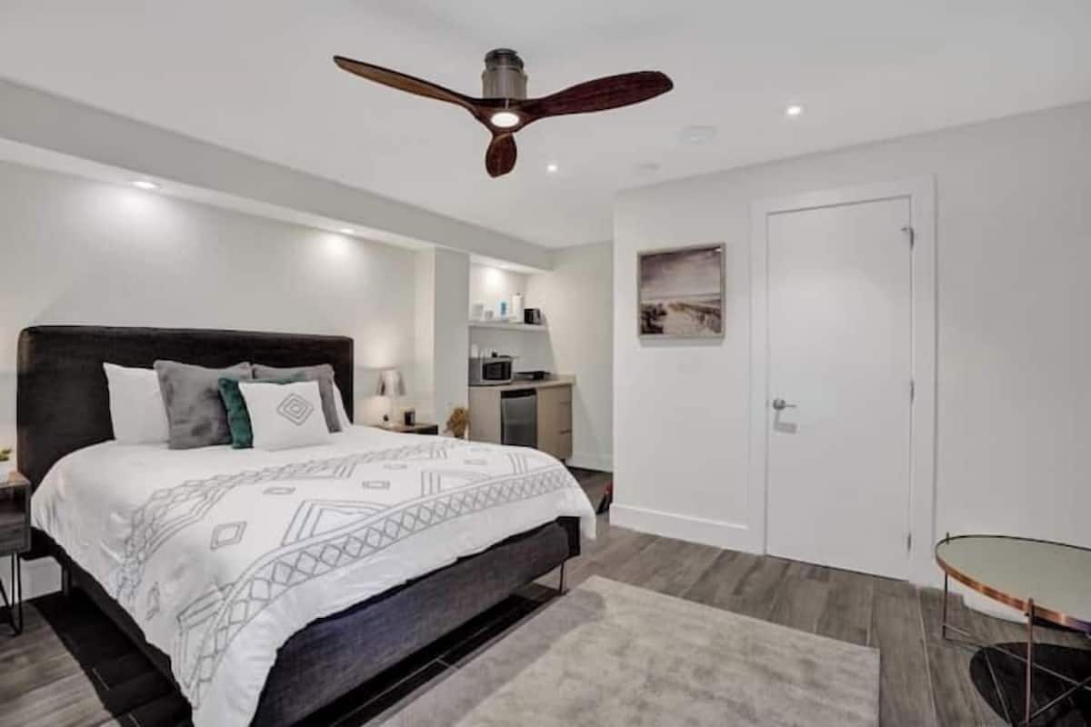 Un dormitorio con cama, mesita de noche y ventilador de techo.