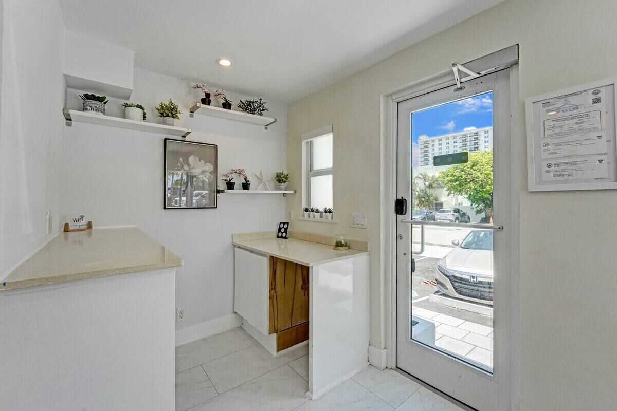 A compact kitchen with a countertop, wooden cabinet, and a window with a view of the street.