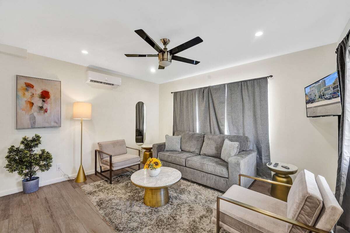 Ein modernes Wohnzimmer mit einem grauen Sofa, einem runden Couchtisch und einem Deckenventilator.