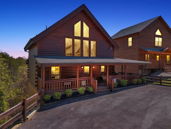 A large wooden lodge with a porch and multiple windows.