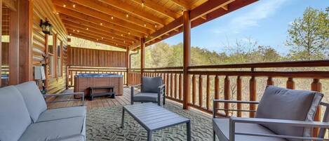 A covered outdoor seating area with a wooden ceiling, a sofa, two chairs, and a small table.