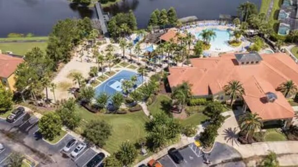 Luchtbeeld van een resort met een zwembad, tennisbanen en een jachthaven.