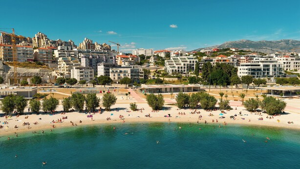 Eine Küstenstadt mit Sandstrand, klarem, blauem Wasser und einer Mischung aus modernen und traditionellen Gebäuden.