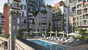 A modern apartment building with a rooftop pool area, outdoor seating, and balconies with greenery. - Qumi Porto Suites (Tivat)