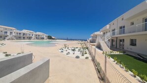 Ein Strandhotel mit mehreren Gebäuden, einem zentralen Pool und einem gepflegten Garten.