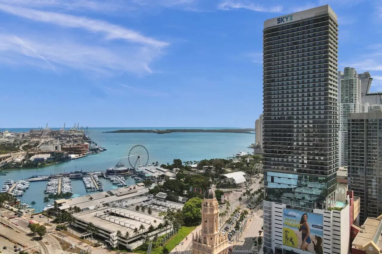 A high-rise hotel with a view of a marina and a Ferris wheel in the background.