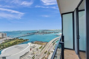 A high-rise building with a view of a marina and a bridge.