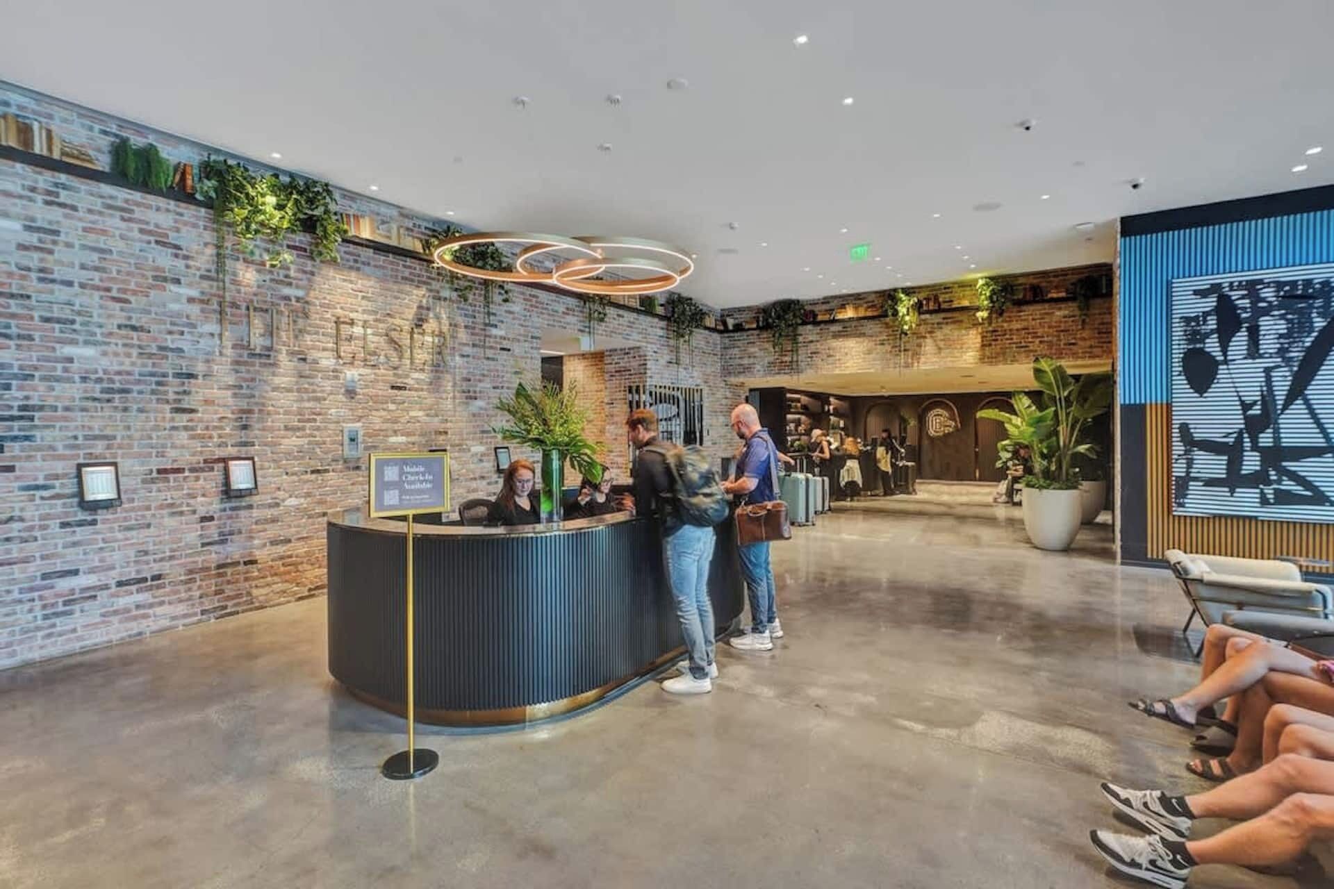 Un espace d’accueil avec un mur en briques, un comptoir de réception et un luminaire moderne.