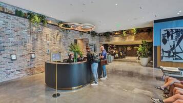 Un espace d’accueil avec un mur en briques, un comptoir de réception et un luminaire moderne.