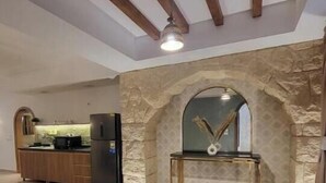 A spacious living area with a kitchen in the background, a stone archway, and a round rug. - 6BRs with private entrance -Three Sisters Villa (New Cairo City)