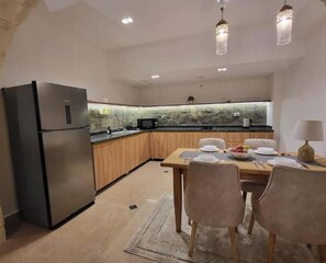 A modern kitchen with a built-in microwave, a refrigerator, and a dining area with a table set for four.