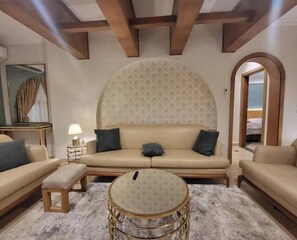 A modern living room with a large sofa, a round coffee table, and a patterned wall.