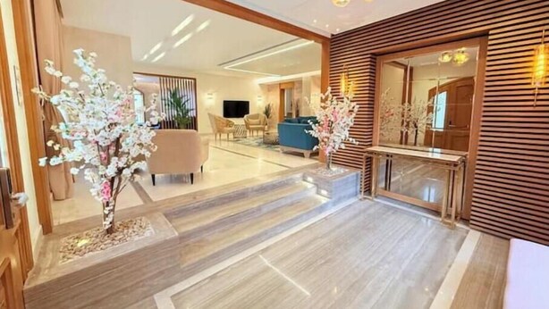 Een moderne hotel lobby met een houten receptiebalie, een zithoek en decoratieve planten.