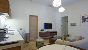 A modern, well-lit kitchen with a dining area, a TV, and a sofa.