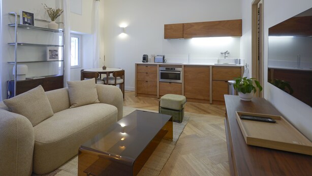 A modern living room with a sofa, coffee table, and a dining area with a table and chairs.