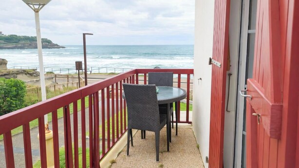 A balcony with a table and chairs, overlooking the ocean with a red railing. - Studio with a beautiful view of the sea of Anglet (Anglet)