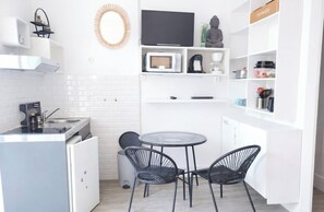A compact kitchen with a microwave, coffee maker, and a small dining table with chairs.