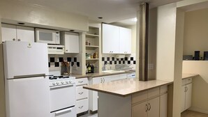 Eine moderne Küche mit weißen Geräten, einer gefliesten Spritzschutzwand und Holzboden.