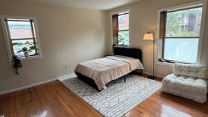 A bedroom with a bed, a nightstand, a lamp, and a window.