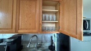A kitchen with wooden cabinets, a built-in microwave, and a stainless steel sink.