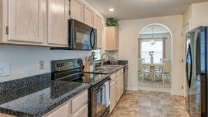 A kitchen with granite countertops, a black stove, and wooden cabinets. - Water View Retreat | spacious 3br w/ lanai (Jacksonville)
