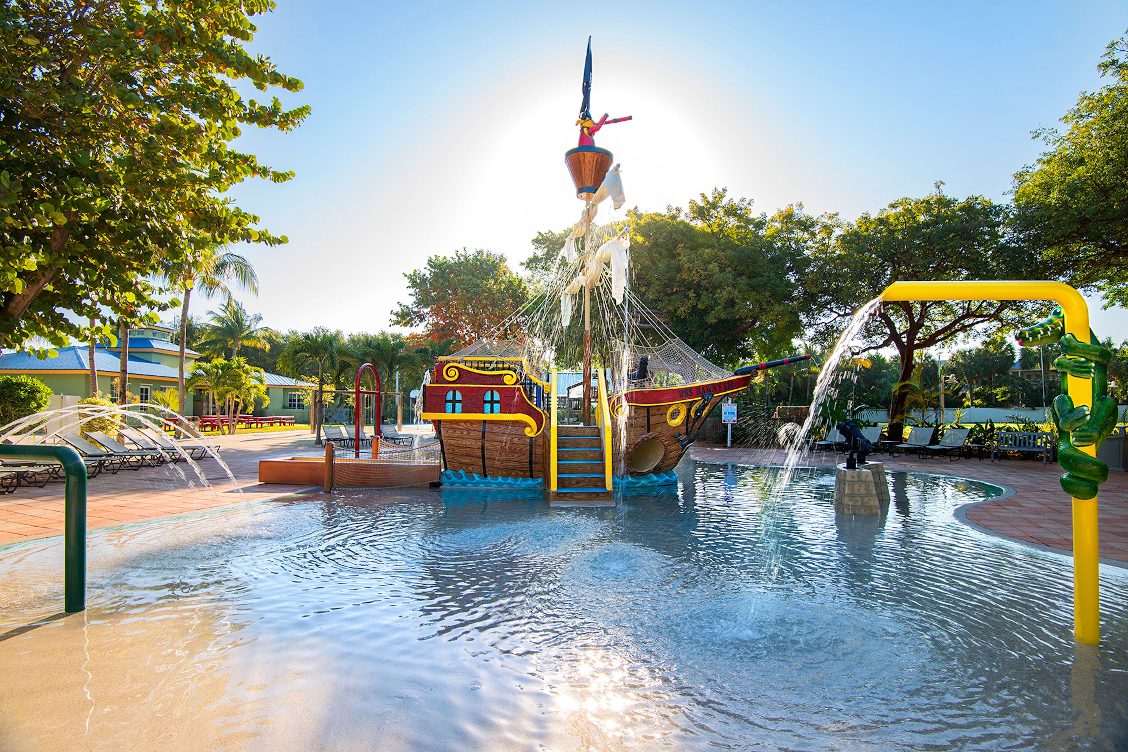 Une fontaine décorée d’un bateau de pirate, entourée d’une piscine et de bancs.