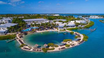 An aerial view of a resort with a central pool, multiple buildings, and a marina.