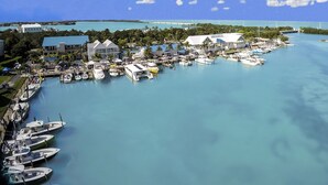 Un port de plaisance où sont amarrés de nombreux bateaux, un bâtiment avec un toit bleu et une vue dégagée sur l’eau et les environs.