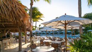Un espace aménagé au bord de la piscine, avec des chaises longues, des parasols et un bar.