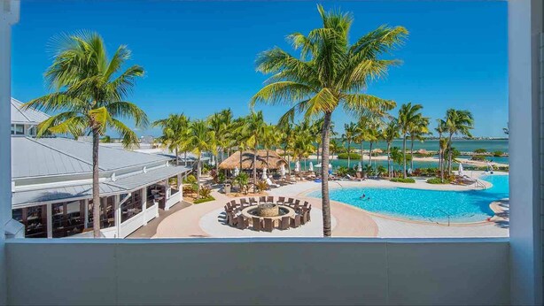 A resort with a swimming pool, palm trees, and a view of the ocean. - Water View King Rm in Duck Key | Spa, Kayak & Pool (Duck Key)