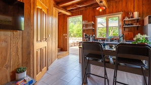 A wooden interior with a kitchen area, a dining table with chairs, and a television mounted on the wall. - Le Chalet Des Oliviers: private pool, Wi-Fi, and air conditioning in Roquefort-la-Bédoule (Roquefort-la-Bédoule)