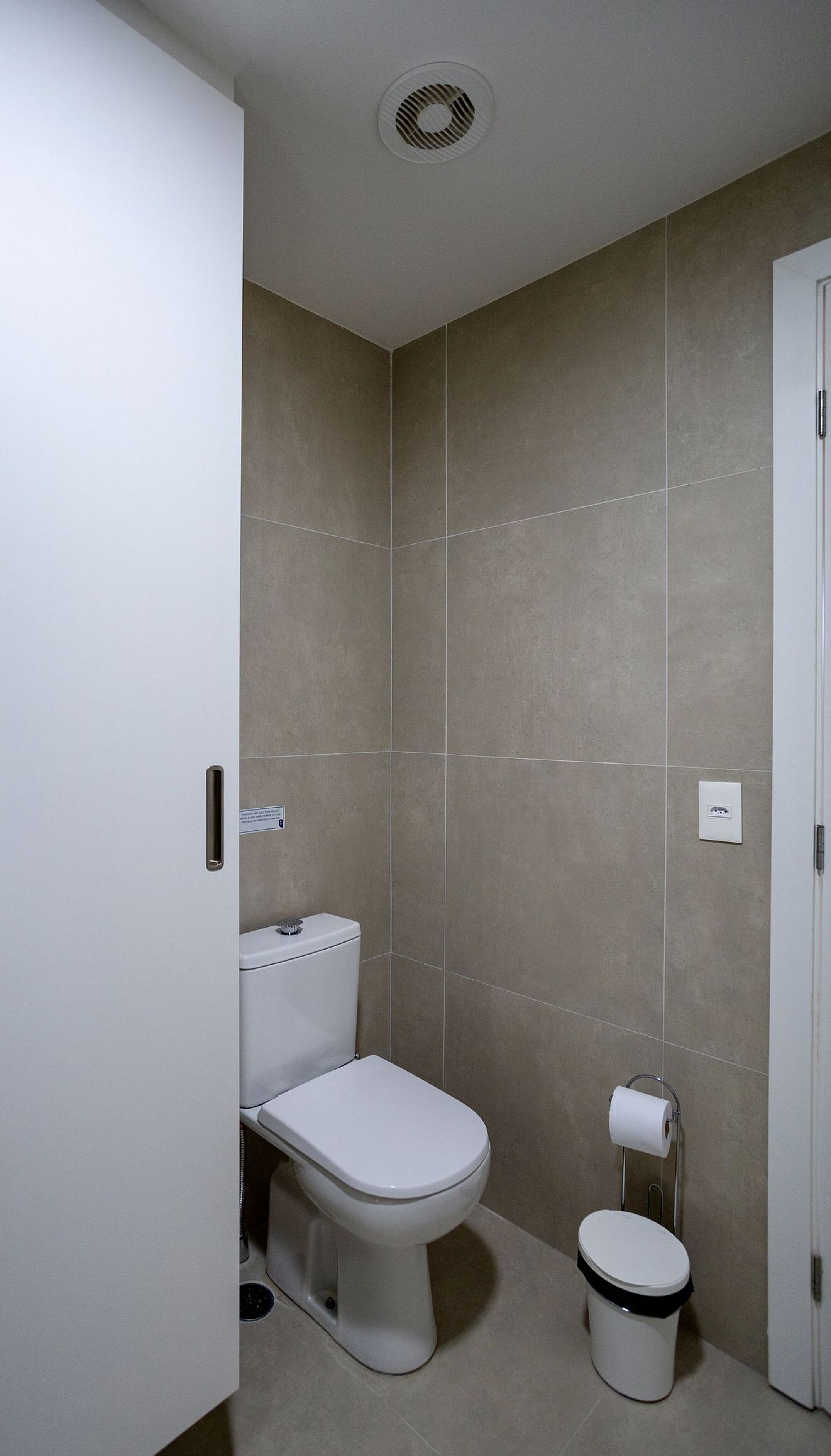 A small, modern bathroom with a toilet, bidet, and a trash can.