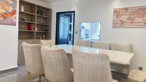 Un comedor con una mesa blanca y sillas a juego, una estantería de madera y un mapa del mundo en la pared.