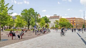 A public square with benches, trees, and people. - Black & White Studio downtown- M2 metro 4-6 tram (Budapest)