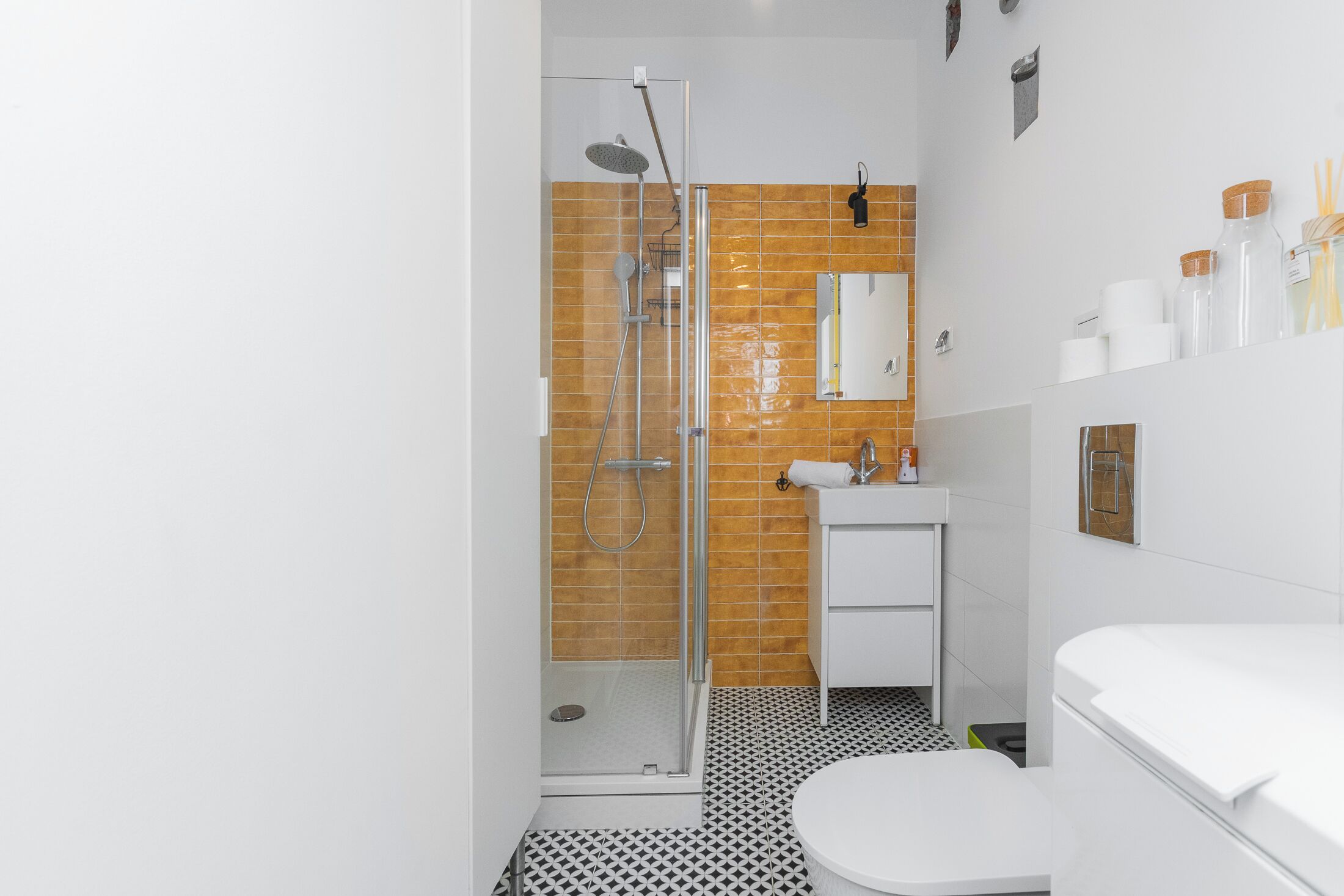 A modern bathroom with a glass shower enclosure, a white sink, and a toilet.