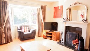 A living room with a sofa, TV, fireplace, and a table.