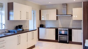 A modern kitchen with white cabinets, a built-in oven, and a stainless steel sink.