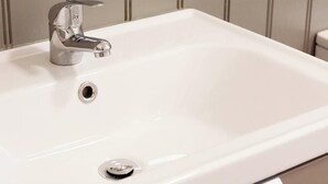 A white bathroom sink with a chrome faucet and a single drain.