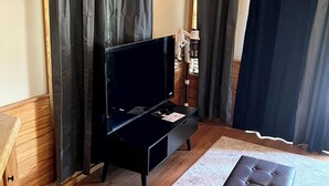 Een kamer met een zwarte bank, een houten salontafel en een geweven stoel.
