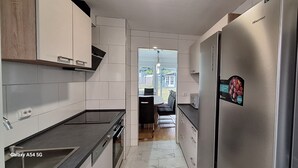 Una cocina moderna con gabinetes blancos, un refrigerador de acero inoxidable y un horno empotrado.