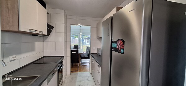 Eine moderne Küche mit weißen Schränken, einem Edelstahlkühlschrank und einem eingebauten Backofen.