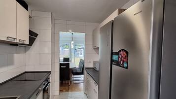 Eine moderne Küche mit weißen Schränken, einem Edelstahlkühlschrank und einem eingebauten Backofen.