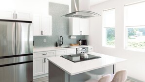 A modern kitchen with white cabinetry, a stainless steel refrigerator, a gas stove, and a large window providing natural light. - Modern Private 3BR w/ ensuites & Garage in Charlotte mins from Airport & Uptown (Charlotte)