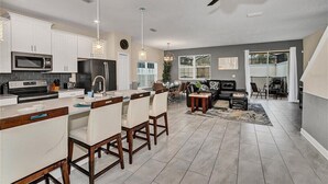 Une cuisine moderne avec des meubles blancs, un îlot central et un coin repas avec des chaises.