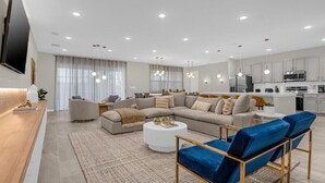A modern living room with a sectional sofa, a coffee table, and blue chairs.