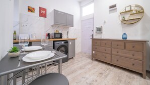 Una cocina compacta con lavadora, microondas y comedor con mesa para dos.
