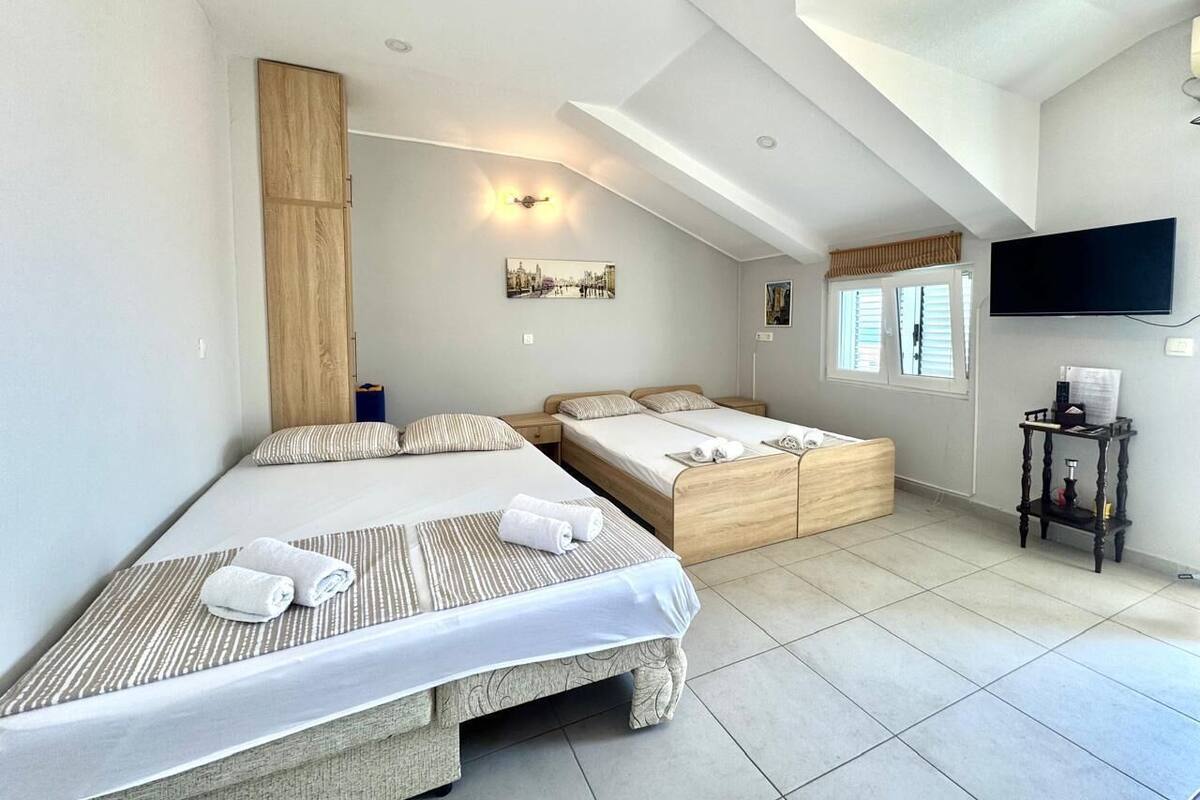 A hotel room with two beds, a TV, and a wooden wardrobe.
